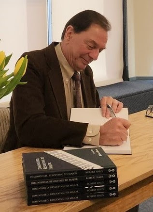 Robert Haus signing his novel with a stack of books nearby